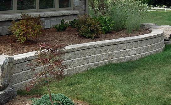 Oaks Ortana retaining wall curving around a raised garden bed
